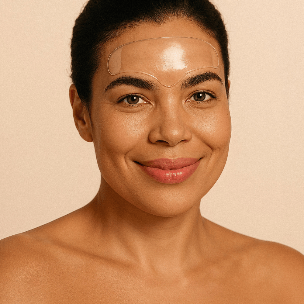 Smiling woman wearing reusable forehead patch for wrinkle-smoothing treatment, targeting frown lines, furrow lines and 11 lines – Bare Intent minimalist skincare